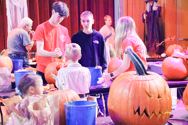 Key Club members help put the finishing touches on someones pumpkin copy